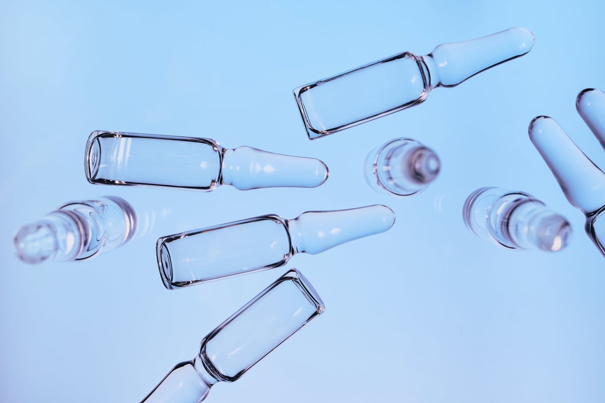 Clear glass ampoules displaying medical supplies and pharmaceutical research on a blue background